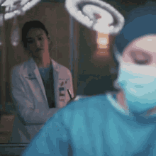 a surgeon in an operating room looks at another surgeon in a mask