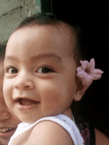 a baby with a pink flower in her ear smiles