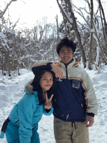 a boy and a girl are posing for a photo in the snow