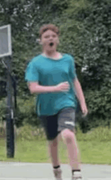 a young man in a blue shirt and shorts is running on a sidewalk .