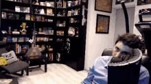 a man sits in a chair with his head resting on the back of it in front of a bookshelf