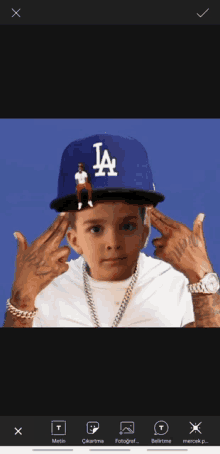 a young boy wearing a la hat holds his hands up to his ears