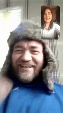 a man wearing a fur hat is smiling in front of a woman