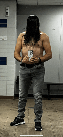 a shirtless man taking a selfie in a locker room