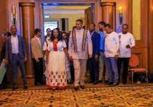 a man and a woman are walking down a hallway surrounded by other people