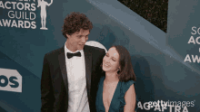 a man in a suit and bow tie stands next to a woman on the red carpet at the actors guild awards