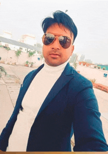 a man wearing sunglasses and a white turtleneck is taking a selfie