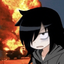 a girl in a hoodie is standing in front of a burning car .