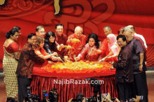 a group of people are gathered around a table with najibrazak.com written on the bottom