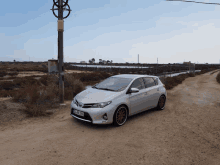 a silver car is parked on a dirt road and has a license plate that says jln 973