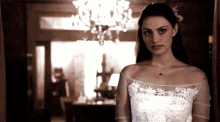 a woman in a wedding dress stands in a dark room