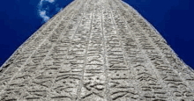 looking up at a large stone obelisk against a blue sky with clouds .