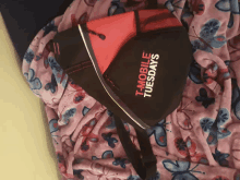 a black and red t-mobile tuesdays bag is laying on a pink blanket