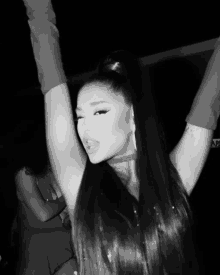 a black and white photo of ariana grande with her hands in the air