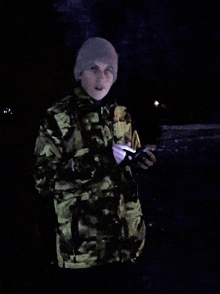 a man in a camouflage jacket is holding a cellphone