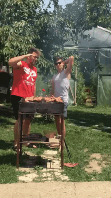 a man wearing a red shirt with the letter x on it stands next to a woman cooking on a grill