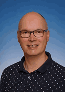 a bald man wearing glasses and a polka dot shirt