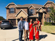 a group of people standing in front of a large brick house with a car parked in the driveway