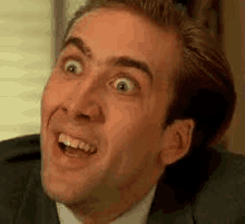 a man in a suit is making a funny face with his mouth open .