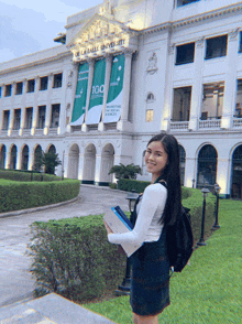 a girl is standing in front of a building that says delasalle university