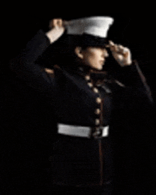 a man in a military uniform is saluting with his hands in the air .