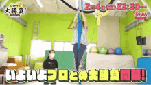 a man is hanging from a rope in a gym with chinese writing on it .