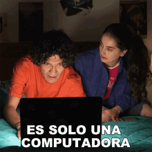 a man and a woman looking at a laptop with the words es solo una computadora