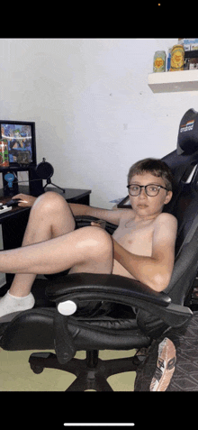 a shirtless boy wearing glasses is sitting in a chair