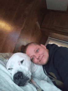 a woman laying on a bed with her head on a large white dog