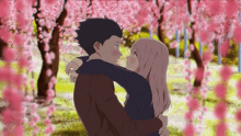 a man and a woman are hugging each other in a park with cherry blossom trees in the background .