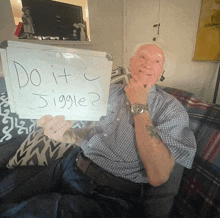 a man sitting on a couch holding a sign that says " do it jiggle "