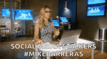 a woman is sitting at a desk in front of a laptop with the words social media stalkers written on the bottom .