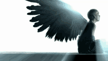 a person with black wings is sitting on a ledge