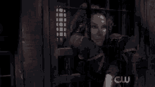 a woman in a cage with a cw logo on the wall