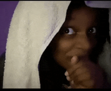 a close up of a person covering their face with a white towel .