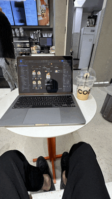 a person sits at a table with a laptop and a cup of coffee that says coffe