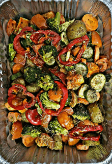 a foil container filled with vegetables including broccoli peppers and sweet potatoes