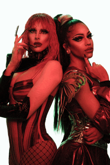 two drag queens standing next to each other with one holding a comb