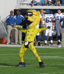 a cheetah mascot on a football field with players in the background wearing numbers 63 and 61