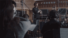 a man stands in front of a group of musicians with a sheet of music that says ' la mer bleue ' on it