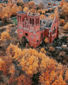 an aerial view of a brick building surrounded by trees and leaves