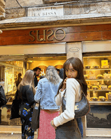 a woman standing in front of a store that says su20