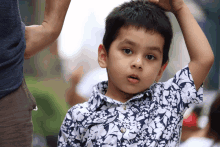 a young boy in a blue and white floral shirt