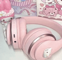 a pair of pink hello kitty headphones are sitting on a table next to a hello kitty doll .