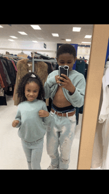 a boy and a girl are taking a selfie in a thrift store