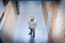 a man standing in a hallway with a brick wall