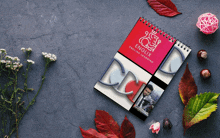 a spiral notebook for english learning sits on a table with leaves and flowers