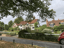 a red car is parked on the side of a road in front of a house