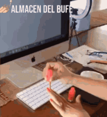 a woman is applying nail polish to her nails while sitting at a desk in front of an apple computer