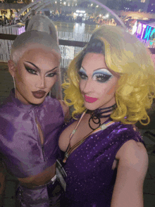 two drag queens posing for a picture with a sign that says art